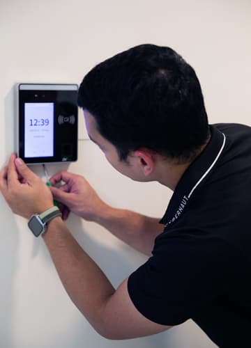 Technician installing a wall-mounted digital biometric face recognition time attendance terminal