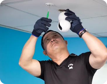 A technician installing cctv security camera onto an office ceiling